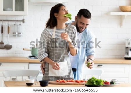 Millennial couple preparing healthy vegetarian salad laughing enjoying process and time with better half on modern cozy kitchen, cooking together during first dating, relish activity at home concept Stock photo © 