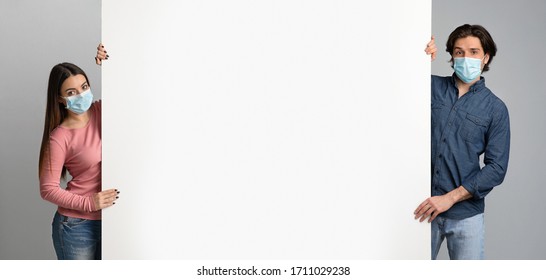 Millennial Couple In Protective Masks Holding Big White Advertisement Board With Free Place For Your Text, Standing Over Light Background, Panorama