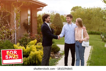 Millennial Couple Shaking Hands With Real Estate Agent Near Their New House Outside, Copy Space