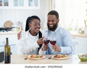 Millennial Couple's Lifestyle. Young Black Lovers Taking Photos On Smartphone While Having Date At Home, Happy African American Couple Drinking Red Wine And Enjoying Tasty Spaghetti, Free Space
