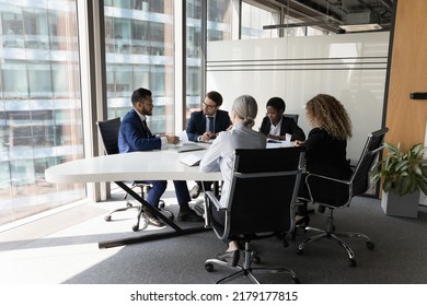 Millennial Diverse Different Aged Business Team Meeting In Modern Office Space. Partners, Stakeholders, Colleagues Negotiating At Conference Table At Panoramic Glass Wall Window