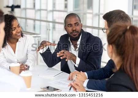 Millennial employees gathered in boardroom for training, black boss ceo leader leading corporate team during seminar learning at modern office. Internship and leadership coaching and education concept