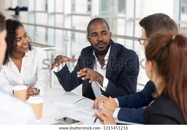Millennial employees gathered in boardroom for\
training, black boss ceo leader leading corporate team during\
seminar learning at modern office. Internship and leadership\
coaching and education\
concept