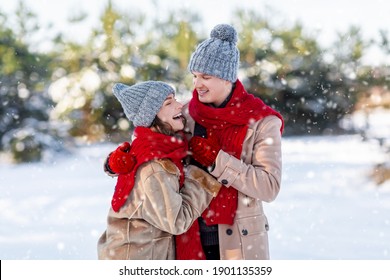 Millennial family spending day in park on snowy sunny day. Emotional young couple having fun while walking by winter forest, loving man hugging his laughing beautiful woman, copy space - Powered by Shutterstock