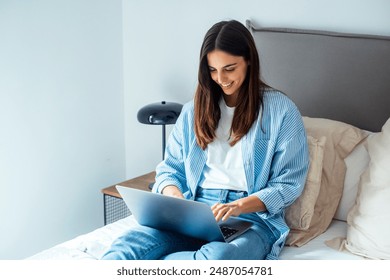 Millennial female resting on sofa holds on lap notebook looking at screen writing e-mail, concept of e-commerce usage, websites surfing, doing remote work at home seated on comfy couch in living room - Powered by Shutterstock