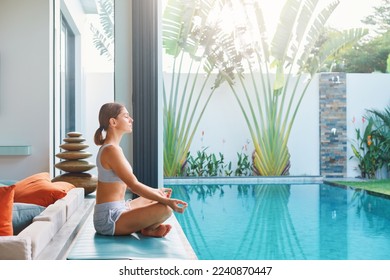 Millennial fit athlete woman making yoga stretching exercises in open air on tropical villa by swimmimng pool Thailand Resort vacation getaway Health care, mental health, wellbeing through meditation - Powered by Shutterstock