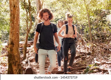 Millennial Friends Hiking Together Downhill On A Forest Trail, Full Length