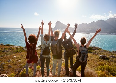 Millennial friends on a hiking trip celebrate reaching the summit and admire the view, back view - Powered by Shutterstock