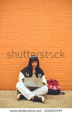 Millennial generation girl sitdown on city street using laptop while waiting for class. Concept student, social network