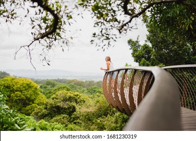Millennial girl in National Botanical Garden, South Africa. Young female traveller enjoying lookout from wooden touristic pathway. Travelling tourist and preserved nature concept.