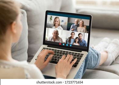 Millennial girl relax on sofa at home talk chat with diverse relatives on video call using laptop gadget, young female rest on couch have webcam conference conversation with family on computer