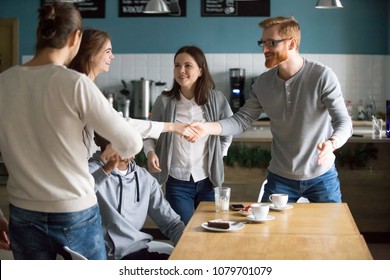 Millennial guy handshaking smiling girl introducing greeting at group meeting in cafe, happy young people get acquainted hanging together at public place, making new friends, first impression concept - Shutterstock ID 1079701079
