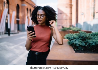 Millennial hipster girl in checking email box notifications on smartphone application while standing outdoors . female buying tickets in baking application, attractive young woman using mobile phone - Powered by Shutterstock