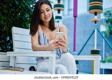 Millennial Hipster Girl Writing Email Message For Sending Via Application On Cellphone Technology, Young Female Blogger Making Online Payment For Bill Via Banking App While Resting In Street Cafe