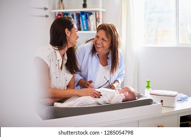 Millennial Hispanic Mother And Grandmother Playing With Baby Son On Changing Table, Selective Focus