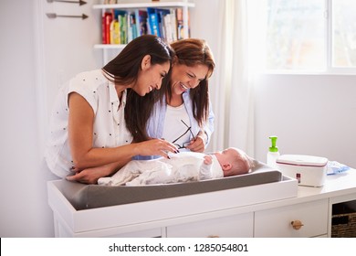 Millennial Hispanic Mother And Grandmother Playing With Baby Son On Changing Table, Selective Focus