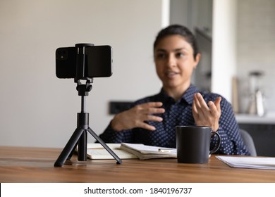 Millennial Indian female vlogger or coach record video live broadcast on smartphone at home. Confident ethnic woman trainer or blogger shoot vlog or course on cell. Online communication concept. - Powered by Shutterstock