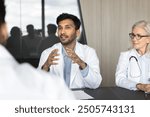 Millennial Indian male doctor speaking, sharing insights, presenting information during group seminar with colleagues, engaged in professional interaction and knowledge exchange. Medical council event