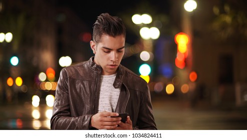 Millennial Latino Man Receiving Cell Phone Call On City Street At Night