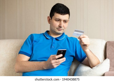 Millennial Man holding credit bank card and using smartphone, mobile at home. Online Payment, Purchase, shopping, e-commerce, internet banking, spending money, Entering Transaction.