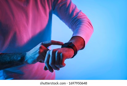 Millennial Man In Neon With Smartwatch On Hand