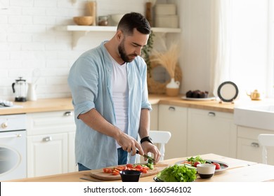 Millennial man stand at modern kitchen table chop vegetables prepare fresh vegetable salad for dinner or lunch, young male cooking at home make breakfast follow healthy diet, vegetarian concept - Powered by Shutterstock