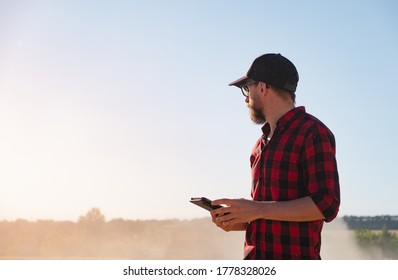 Millennial man with a tablet in a dusty agricultural field. Modern farming, agriculture business, harvest management - Powered by Shutterstock