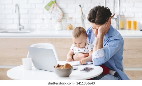 Millennial Man Tired Of Working And Taking Care Of Baby, Covering Face In Despair. Little Boy Playing With Notebook, Kitchen Interior, Free Space