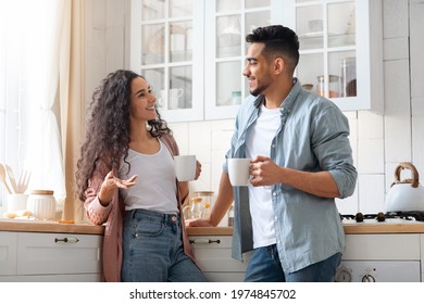 Millennial Middle Eastern Couple Spending Time In Kitchen Together, Drinking Coffee And Chatting, Cheerful Young Arab Man And Woman Enjoying Hot Drinks And Smiling, Relaxing At Home, Free Space