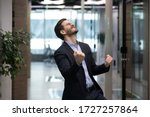 Millennial office worker in suit standing in hallway clenched fists feel overjoyed celebrate career advancement, got business opportunity, salary or sales growth, successful winner businessman concept