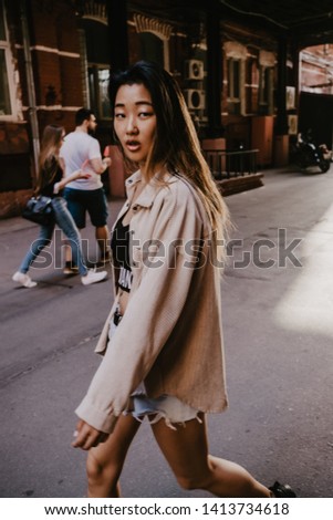 Millennial pretty asian girl posing on city streets. Minimalist urban clothing style
