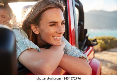 Millennial white woman on a road trip with friends leaning on car door enjoying view, close up - Powered by Shutterstock