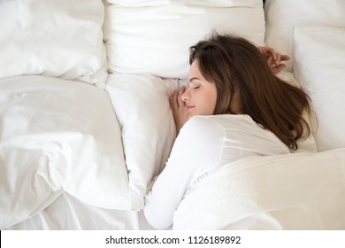 Millennial woman sleeping well on soft pillow and comfortable bed mattress with white cotton sheets under warm duvet having good night sleep enjoying sweet dreams and enough rest concept, top view - Shutterstock ID 1126189892