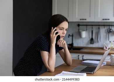 Millennial woman standing in domestic kitchen make call having conversation looks serious or concerned listen news, talks to client solve issues from home. Modern tech, remote communication concept - Powered by Shutterstock