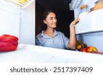 Millennial woman taking vegetal milk bottle from fridge, view from inside