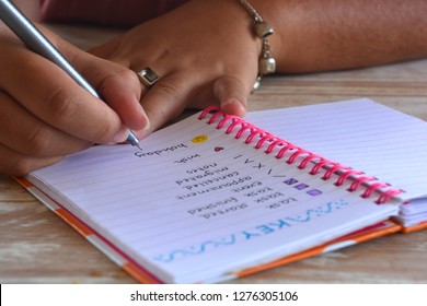 Millennial woman writing in a bullet journal, pen in hand