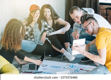 Millennials business routine. Young people cooperating in modern loft office, sitting on floor. Positive working climate.
