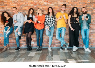 Millennials happy wealthy generation. Young cheerful people in casual outfits, standing relaxed, holding latest smartphones.