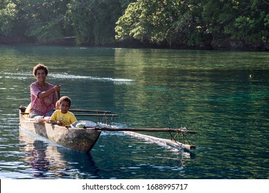 Milne Bay, Papua New Guinea - March 17th 2020 - Family paddling in their canoe to trade goods
