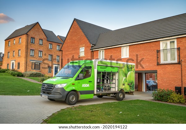 Milton Keynes,England-August 2021: ASDA retailer\
carries out home deliveries of groceries in neighborhood areas\
using vans as this has become more popular among people during the\
Covid-19 pandemic