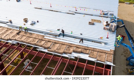 MILWAUKEE, WI, USA - SEPTEMBER 15, 2020: Construction workers installing insulation and roof panels on a large warehouse building.