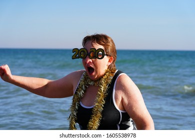 Milwaukee, Wisconsin / USA - January 1st, 2020: Middle Aged Woman Wearing 2020 New Year's Party Glasses Plunged Herself Into The Chilly Cold Waters Of Lake Michigan For The Polar Bear Plunge Event. 