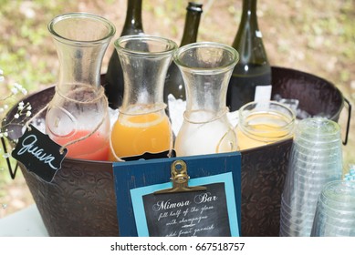 A Mimosa Bar With A Selection Of Fresh Fruit Juices And Prosecco At An Outdoor Party.