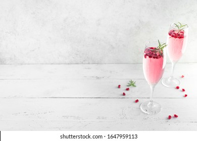 Mimosa Cocktail With Rose Champagne, Pomegranate And Rosemary In Flute Glasses,  Copy Space. Mocktail, Mimosa Sparkling Pink Drink.