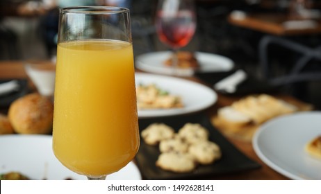 Mimosa On Table With Gourmet Breakfast In The Background