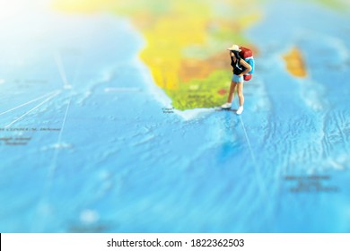 Minature People: Traveling With A Backpack Standing On World Map, Travel And Summer Concept.