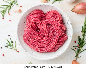 Mince beef, ground meat with ingredients for cooking on white wooden rustic table, top view