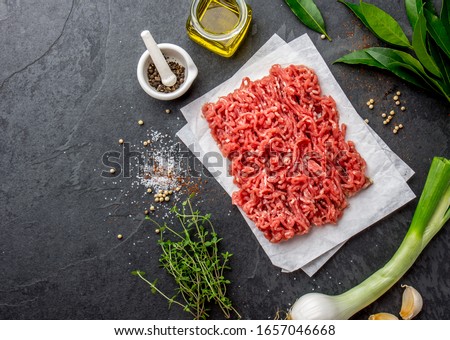 Mince. Ground meat with ingredients for cooking on black background. Minced beef meat. Top view.