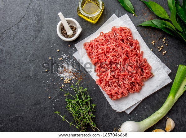 Mince. Ground meat with\
ingredients for cooking on black background. Minced beef meat. Top\
view.