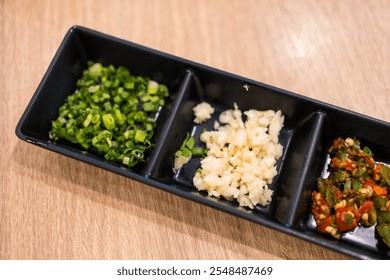 Minced garlic, chili mince and spring onion in the black tray for add to hot pot dip. Close up - Powered by Shutterstock